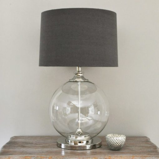 large glass ball shaped table lamp with chrome central pole, base and neck with a dark grey drum linen lampshade