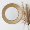 circular wall mirror with a wide ribbed copper frame
