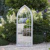 larged arched metal framed garden mirror with a gothic window design and stone coloured frame