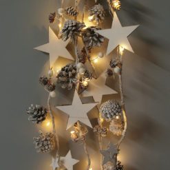 rustic pre-lit Christmas garland decorated with white wooden stars, berries and pine cones, all dusted in glitter and warm white LED lights - 2.2m