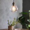 a prism shaped glass pendant light with a brass bulb fitting and black cord