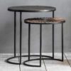set of two round nesting side tables with simple crescent shaped metal legs and two textured metal surfaces - one bronze and one copper with a textured surface