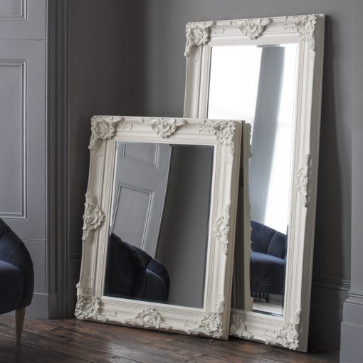 a highly decorative framed wall or floor standing mirror finished in ivory