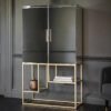 art deco style drinks cabinet with a mirrored cabinet containing three adjustable glass shelves placed on a slim champagne gold metal framed base with two box shelves