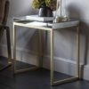 rectangular side table comprising of a champagne gold metal framed base and raised mirrored glass top