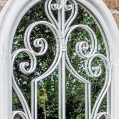 distressed white arched outdoor garden mirror with a decorative scroll design
