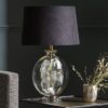 flat clear round glass table lamp base with gold inner pole and accents topped with a black velvet tapered lampshade with gold lining