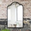 large iron framed industrial style mirror with a curved top and distressed black finish