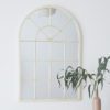 cream metal framed arched window mirror with a lightly distressed finish