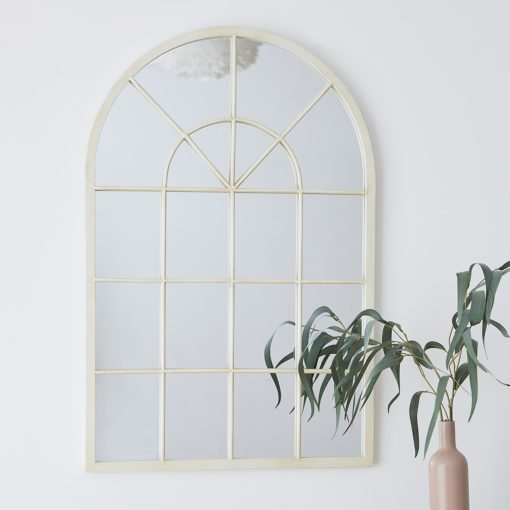 cream metal framed arched window mirror with a lightly distressed finish