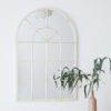 cream metal framed arched window mirror with a lightly distressed finish