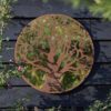 round garden mirror with a rusty metal frame featuring a woodland overlay