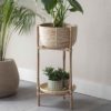large rattan plant stand with round basket on top and plant tray underneath