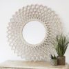 large round wooden wall mirror with carved cut-out design and painted white finish with warm gold detail