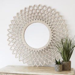 large round wooden wall mirror with carved cut-out design and painted white finish with warm gold detail