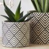 two round cement plant pots with a geometric monochrome design available in two sizes