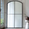 oversized large floor standing window wall mirror with a curved top and black industrial metal frame