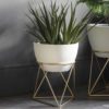 set of two ivory planters with a textured finish set in a gold geometric metal framed stand