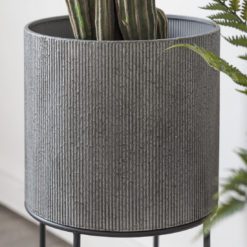 set of two round industrial style grey metal planters with a ribbed design set on a black framed stand