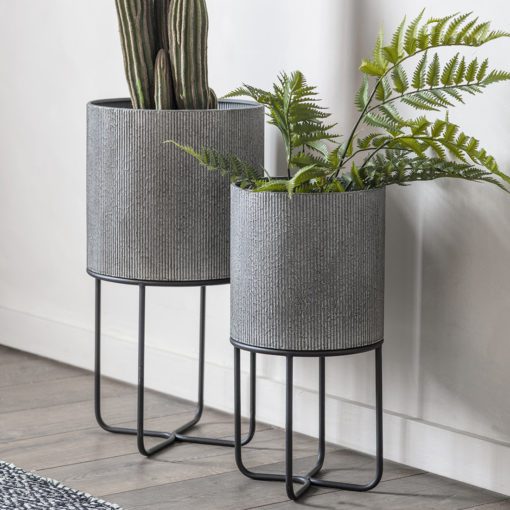 set of two round industrial style grey metal planters with a ribbed design set on a black framed stand