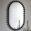 curved pill shaped wall mirror with a black metal bobble frame