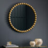 round wall mirror with a textured large bobble frame in a warm gold finish