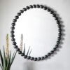 round wall mirror with a black metal bobble frame