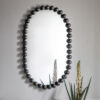 curved oval shaped wall mirror with a black metal bobble frame