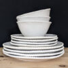 set of four white porcelain plates and bowls with an uneven rustic shape and beaded edging