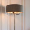 polished silver stemmed floor lamp with a three-arm light fitting and grey linen lampshade