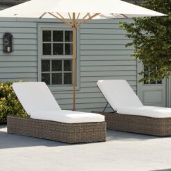 large rattan sun lounger with an adjustable back and off-white cushions