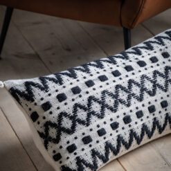 black and cream rectangular bolster cushion with a bold aztec pattern and four large cream corner pom poms