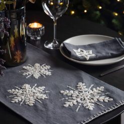 dark grey cotton table runners in two sizes with a large embroidered white snowflake and blanket stitching