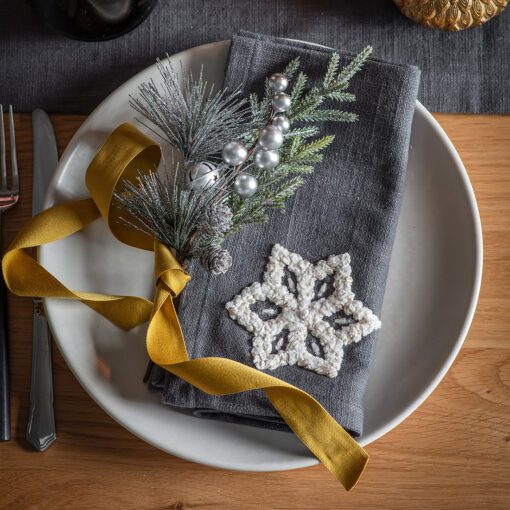 set of four dark grey cotton napkins with a large embroidered white snowflake