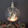 retro styled glass bulb hanging christmas decoration with a pre-lit reindeer, bristle brushes and irredescent snow
