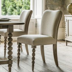 two handcrafted oak dining chairs with turned bobbin front legs and a natural upholstered seat