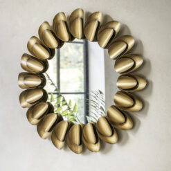 decorative round metal wall mirror with a wide frame made up of two layers of large petal shapes finished in a warming bronze metallic