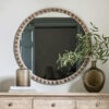 large round wooden wall mirror with a chunky bobble design frame and a light white wash finish