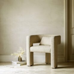 contemporary natural curved armchair with bolster cushion upholstered in a warm natural textured fabric