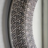 round wall mirror with a wide metal frame with a decorative filigree design finished in a pewter tone