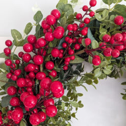 large faux christmas wreath with a sturdy round twig base adorned with mixed foliage stems and bursting with red berries