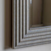 decorative square wall mirror with a stepped ribbed wide frame and distressed silver finish