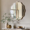 decorative round wall mirror with a wavy silm metal frame finished in gold leaf