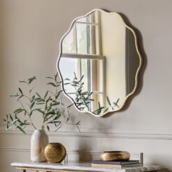 decorative round wall mirror with a wavy silm metal frame finished in gold leaf