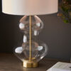large glass table lamp with a clear hourglass silouette, satin brass accents and vintage white drum lampshade