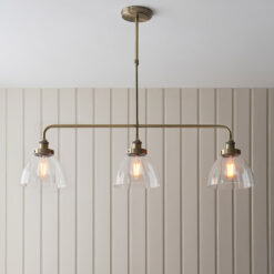 industrial style antique brass linear light with three glass domed hanging pendants