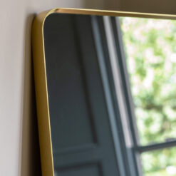 generously oversized full length rectangular mirror with curved corners and a slim metal frame finished in a warming gold