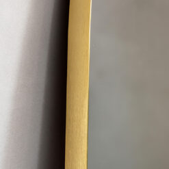 full length mirror with fluid curved edging and a slim metal frame finished in a warming gold