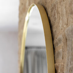 large arched overmantle wall mirror with a slim metal frame finished in warming gold