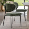 forest green retro style dining chairs with a cushioned seatpad, oval shaped back rest and black metal legs